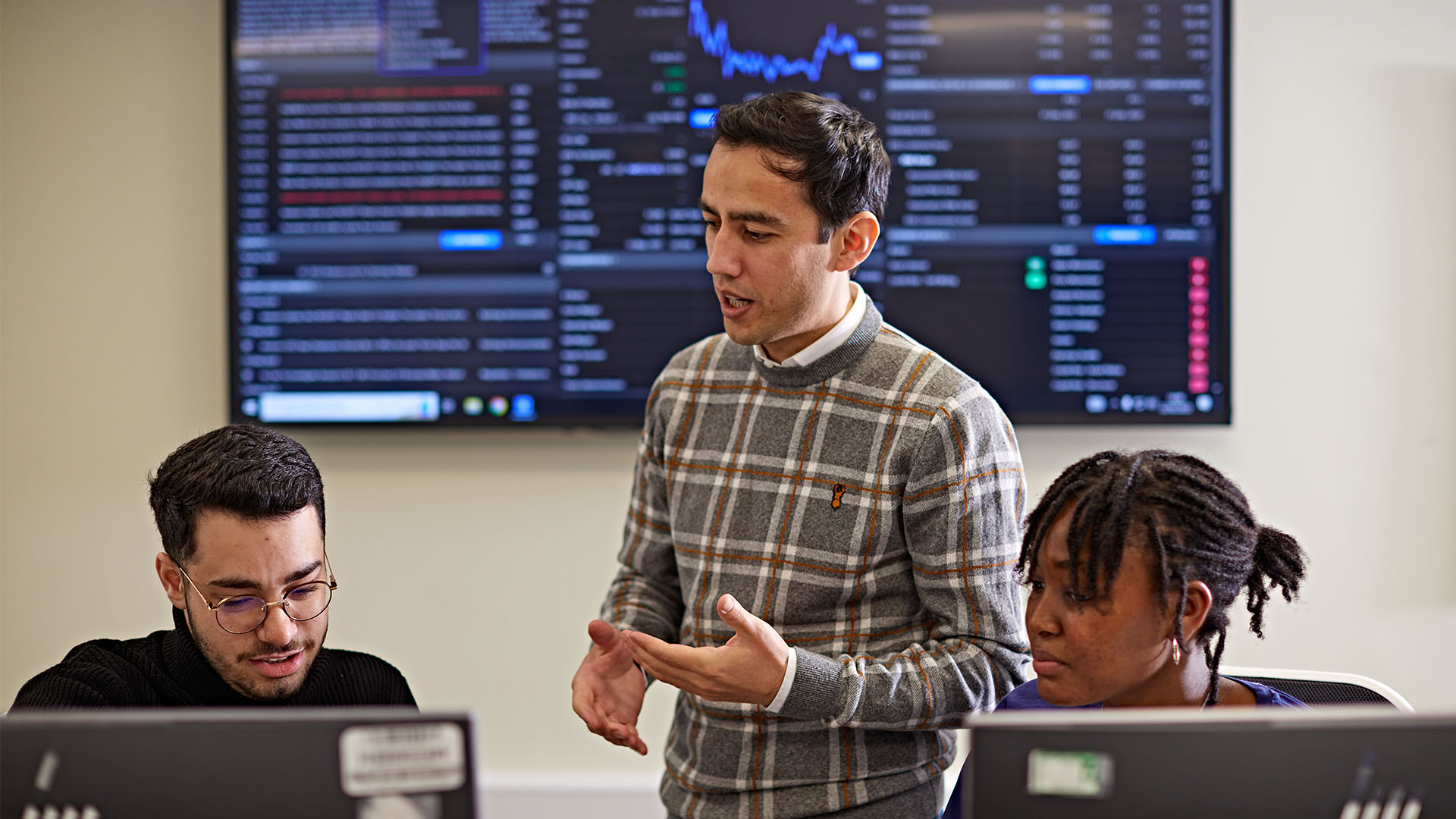 Students in trading room in front of large trading screen