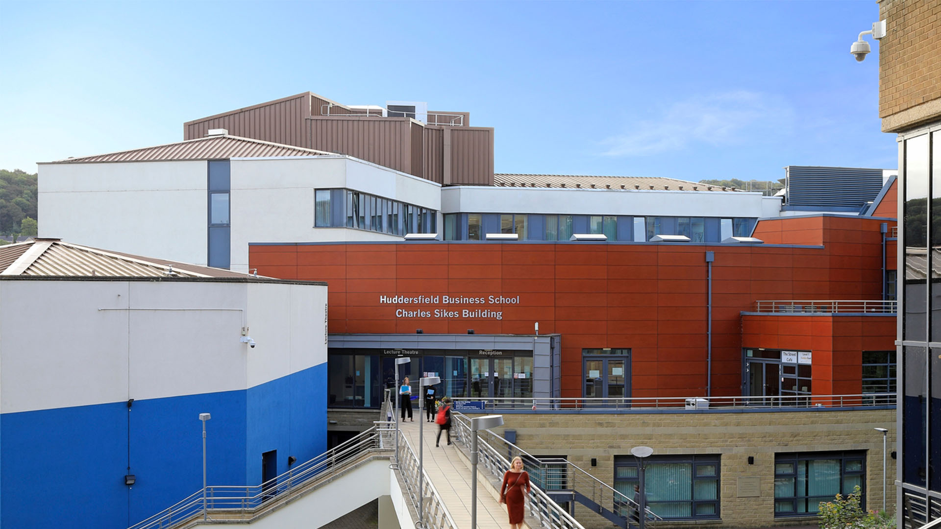 Charles Sikes building from above, on a sunny day with staff and students walking on the attached bridge