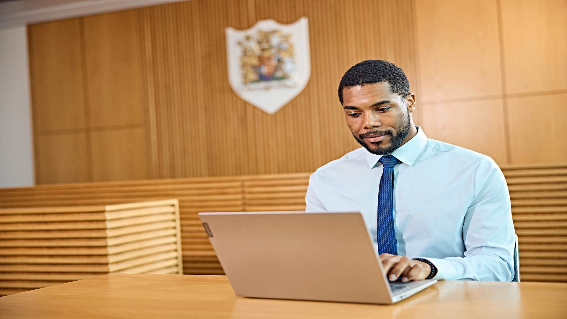 A man working on a laptop in a court room.