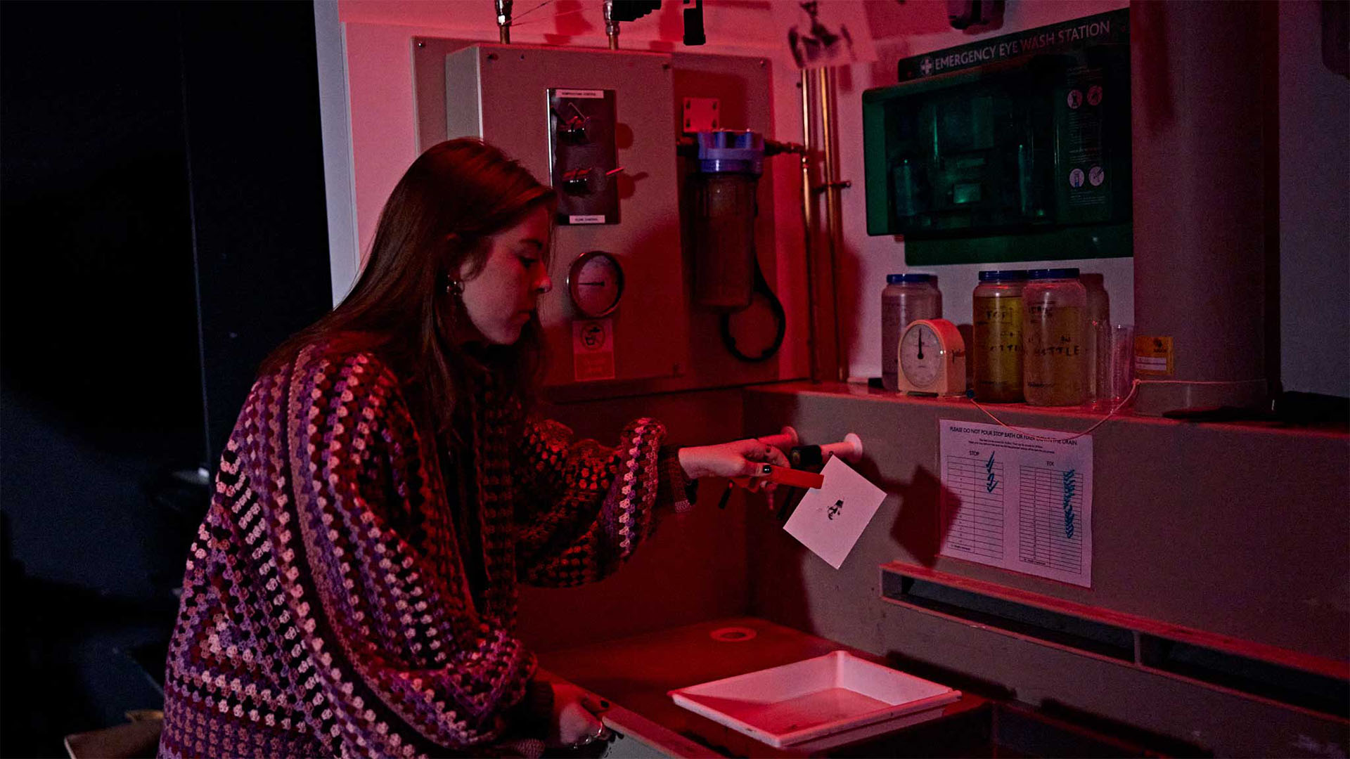Student developing photographs in a dark room
