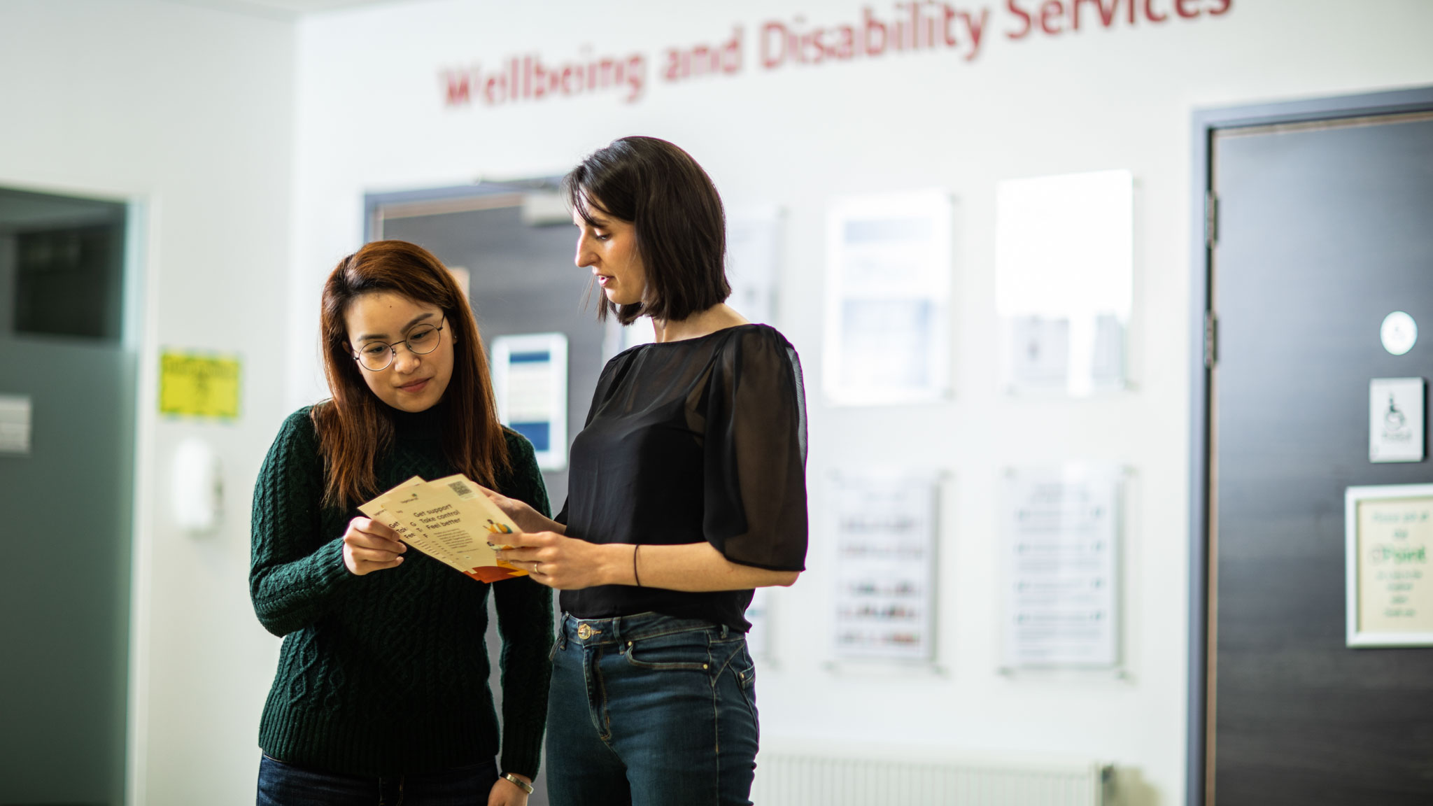 Student talking to support reading a pamphlet