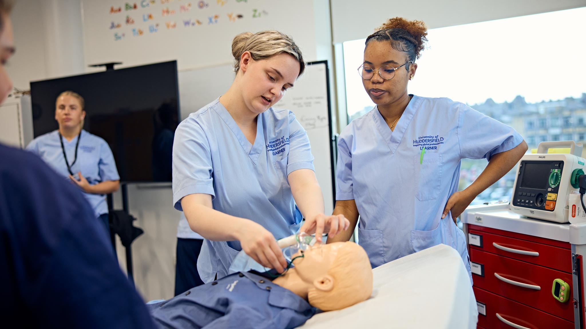 Two students learning how to use an oxygen mask on a medical manikin