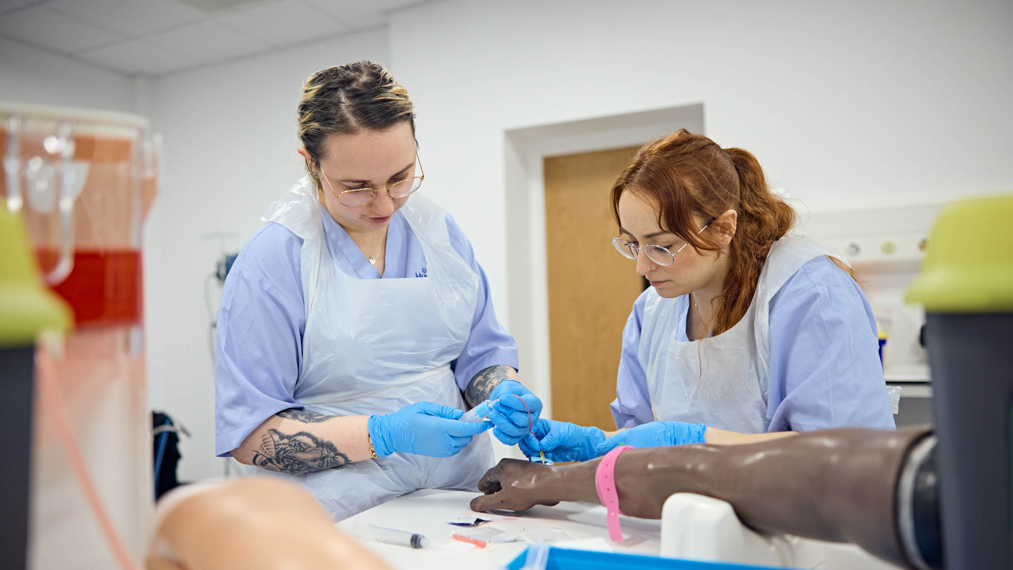 Two students learning how to use medical equipment
