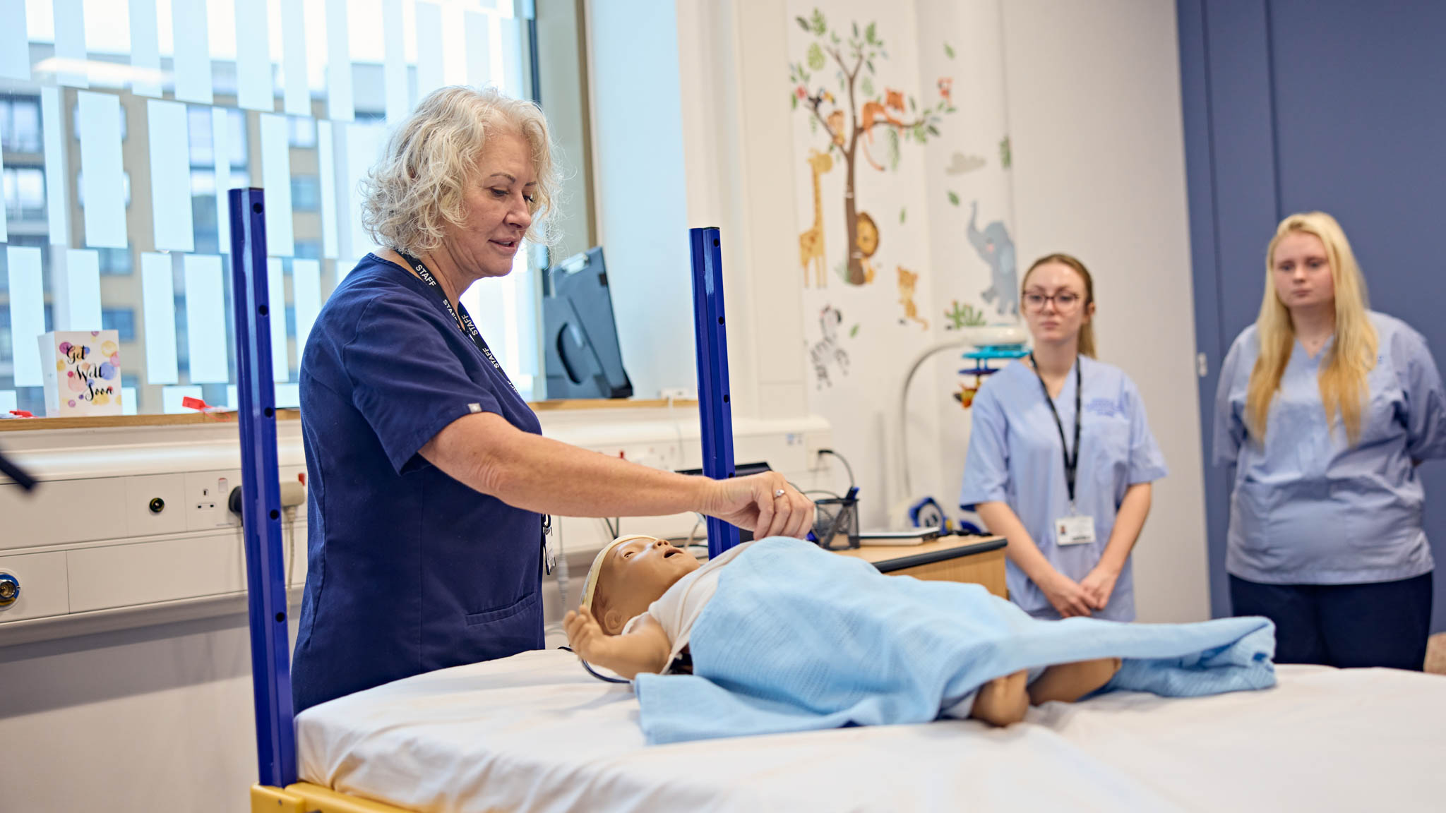A nursing lecturer in one of our hospital simulators teaching students who are watching
