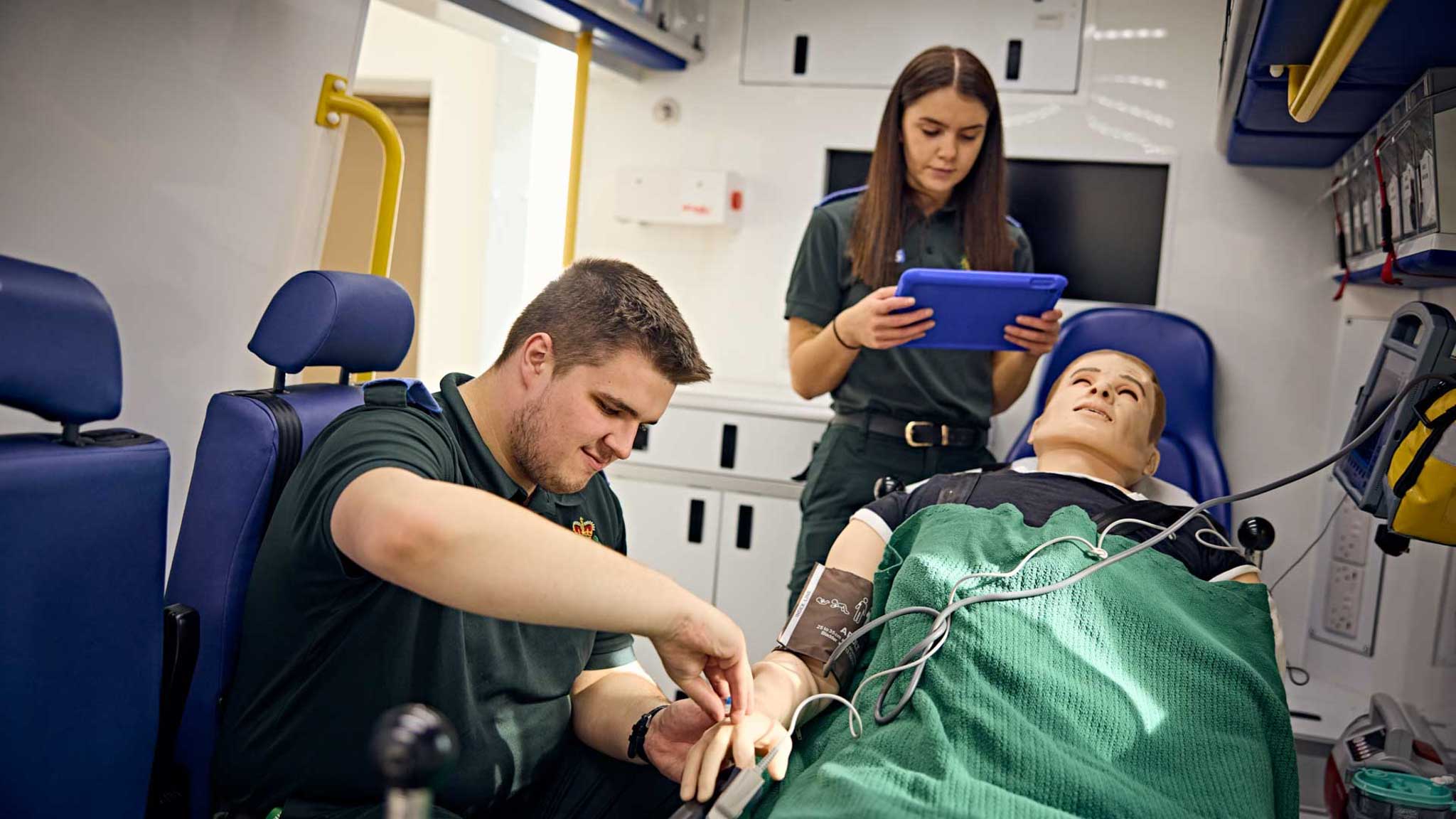Students using the simbulance as an area of practice for clinical skills. Performing an intravenous cannulation on a patient to deliver the required drugs