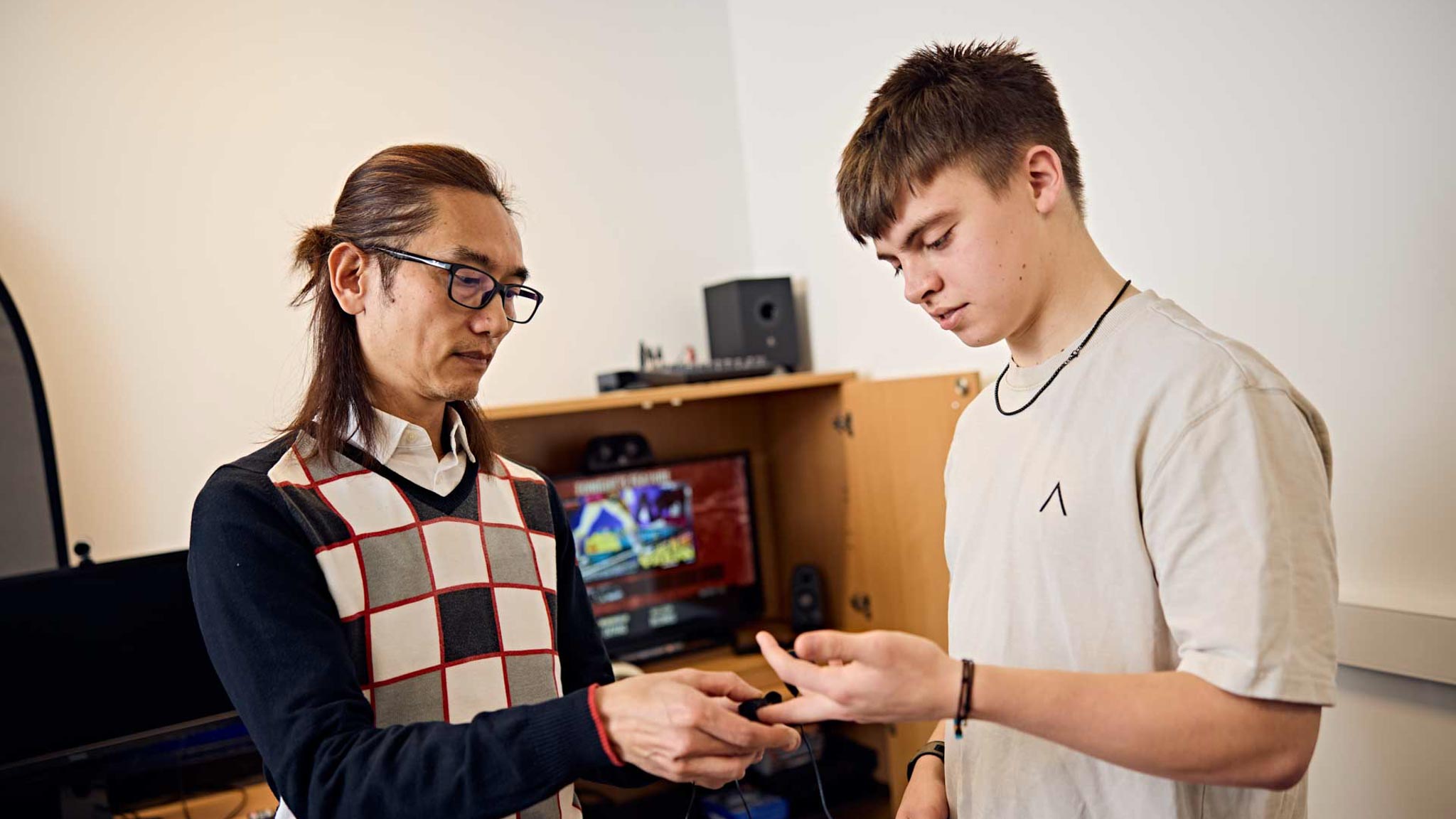 A psychology student and lecturer adjusting the finger sensors of a psychophysiology measuring device before conducting an experiment
